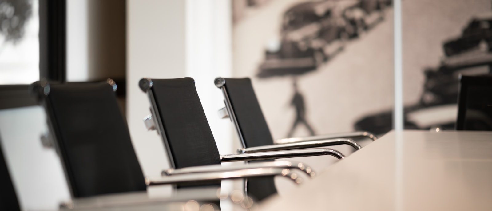 Black office chairs with chrome arms in a row at a conference table